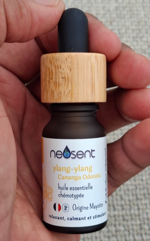 Flacon d'huile essentielle d'ylang-ylang Neosent tenu dans la main
